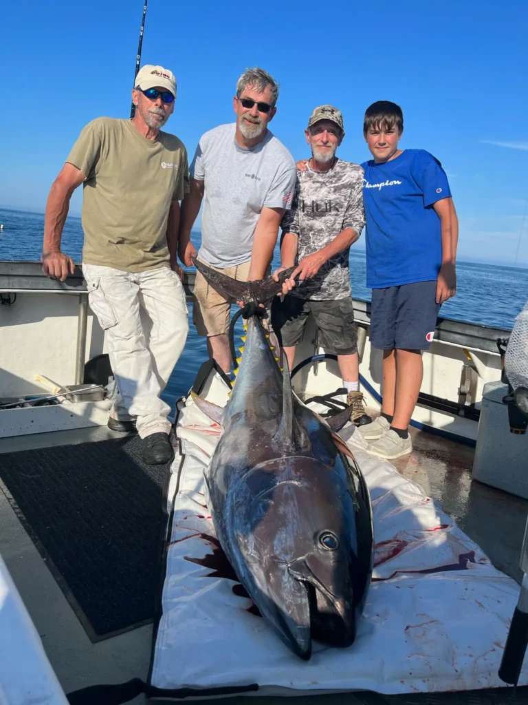 deep sea fishing gloucester a group of fishermen holding a bluefin tuna catch on the back of Willow Gray Charters boat